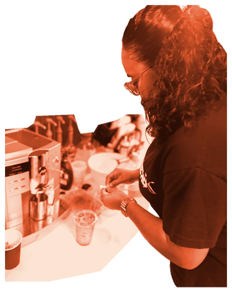 A volunteer making iced coffee at the café espresso station