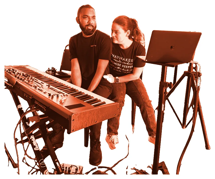 Two worship team members at the keyboard during rehearsal