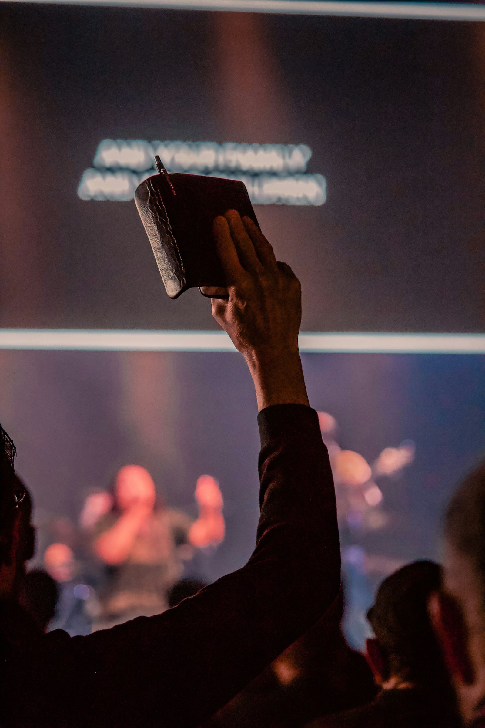 A worshiper lifting a Bible during a worship gathering