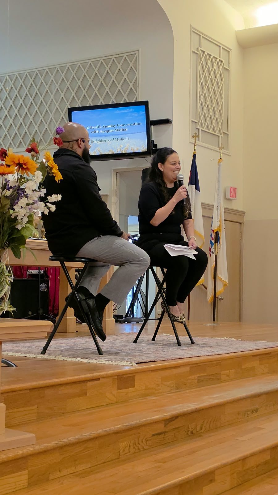Jacquie Mathai of Neighborhood Medical leading a health conversation on stage during a Sunday gathering
