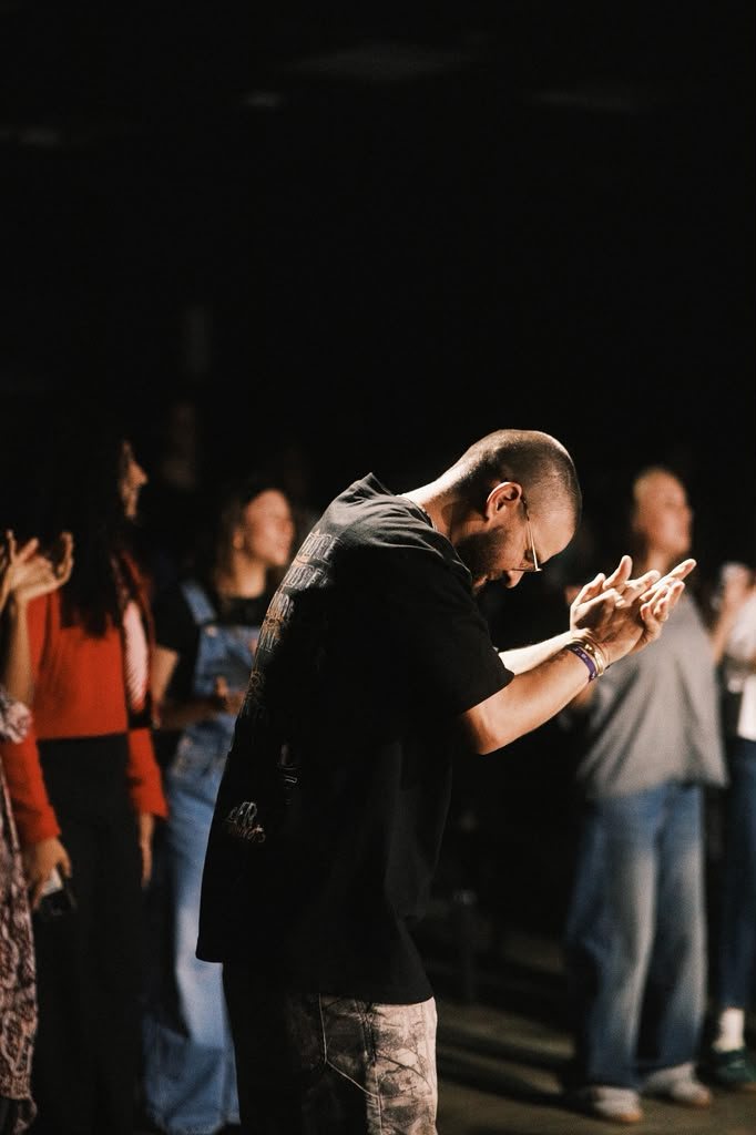 A young adult bowing in worship with hands lifted